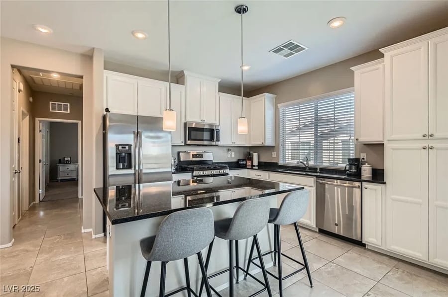 White kitchen with island and pendant lights in a home sold by Park Place Realty, Las Vegas