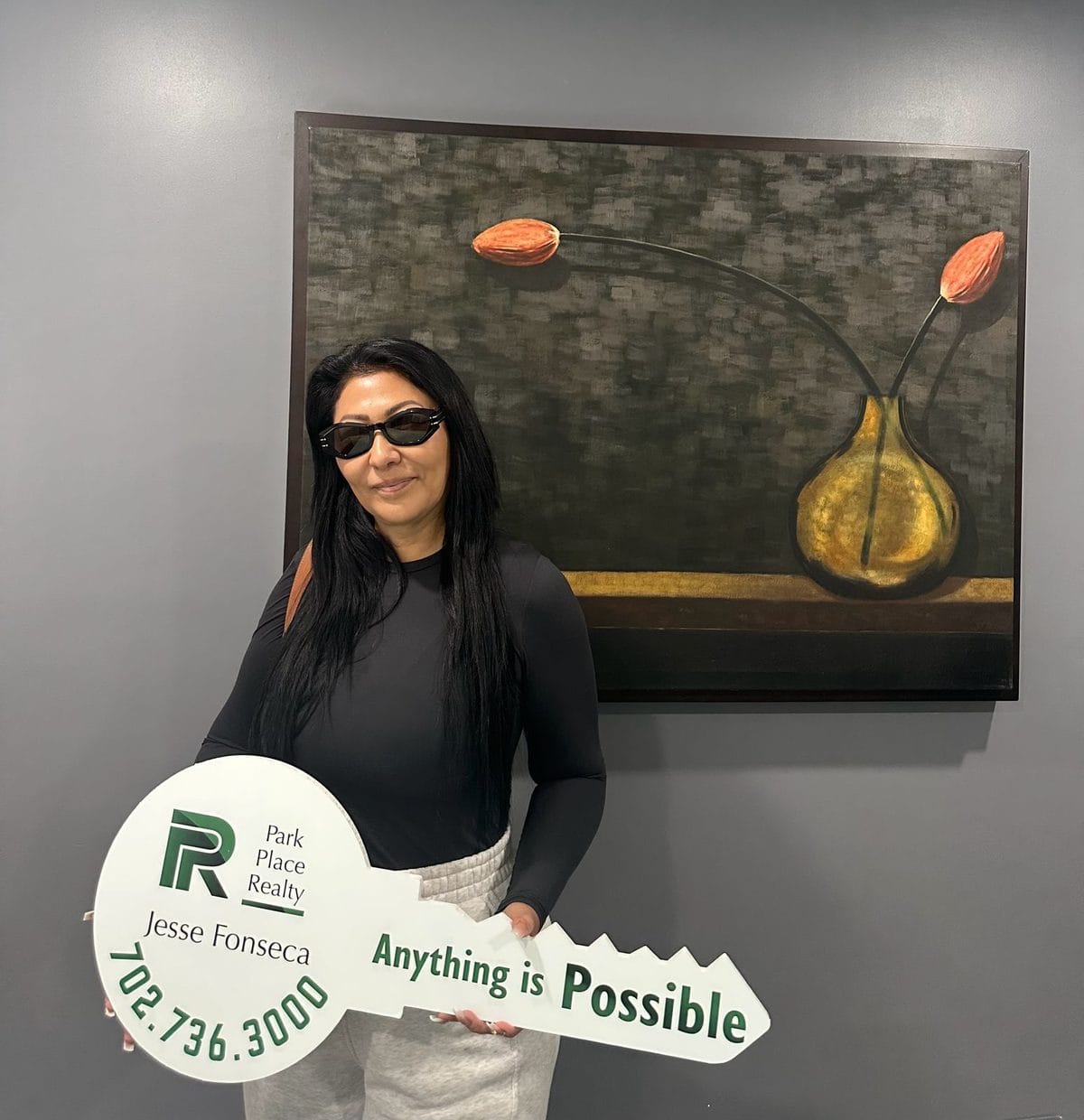 A Park Place Realty client holding the closing-day key at the Jones Blvd. office
